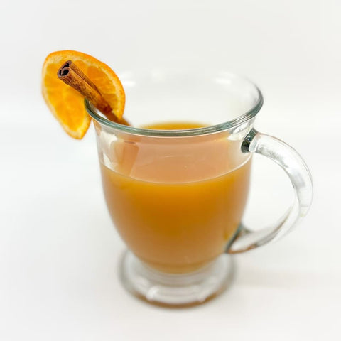 Mug of honey spice holiday wassail garnished with orange slice and cinnamon stick