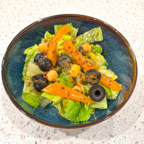 Salad with dressing in blue bowl on white countertop