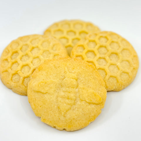 Honey butter shortbread cookies with bee and hexagonal designs on white background.