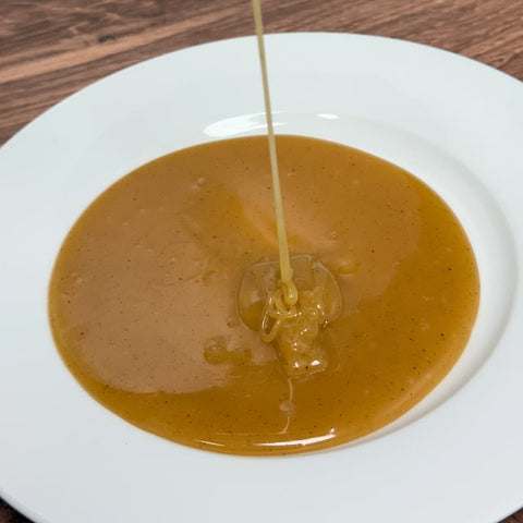 Caramel sauce on white plate on wooden surface.