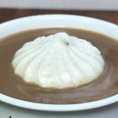 Honey marshmallow floating in dish of brown liquid