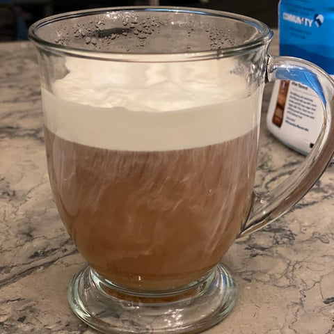 Cold foam topping a hot beverage in a glass mug