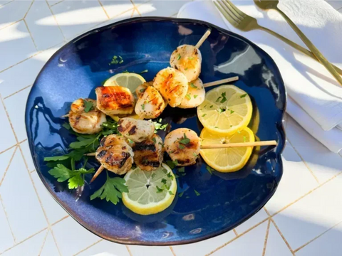 Skewers and lemon wedges on blue plate sitting on white patterned background