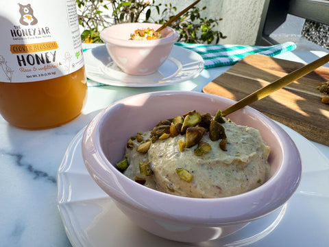 Bowl of Nice Cream topped with nuts in a pink bowl in front of jar of honey and second bowl.