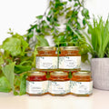 Jars of honey with labels on a surface with plants in the background