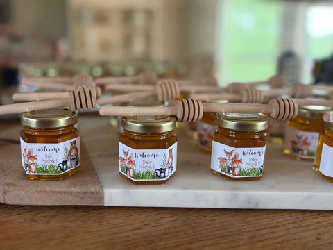Jars of honey with labels and honey dippers on wooden surface