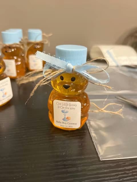 Small bottle of honey in a bear-shaped container with a decorative bow on a table