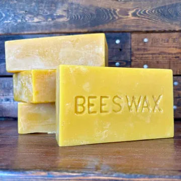 Beeswax bars stacked on a wooden surface with a rustic background