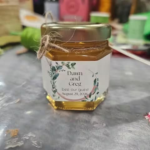 Jar of honey with personalized label on a textured surface.