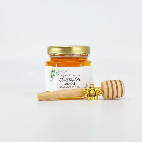 2 oz hexagon jar filled with honey, gold lid, 3" wooden honey dipper, enamel honeycomb charm, and personalized eucalyptus design on label with title The Baptism of Christopher James.