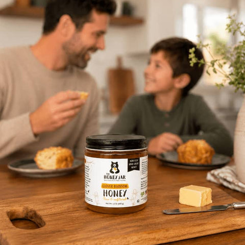 Man and child at a table with a jar of honey on a wooden board