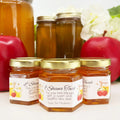 Close up of 2 oz Rosh Hashanah New Year favors on hexagon jars with gold lid with personalized honey and apples labels. Label title shown is L'Shana Tovah.