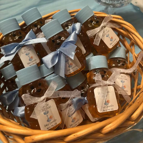 Basket of small honey bottles with blue caps and ribbons on a table.