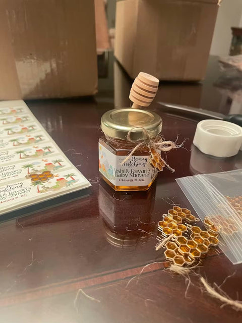 Jar of honey with a honey dipper and scattered charms on a table