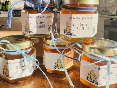 stack of jars of honey with personalized labels and blue ribbon