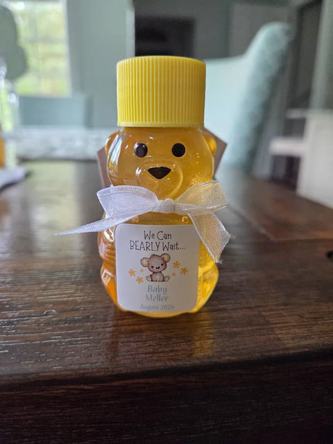 Honey bear with yellow lid and white bow on wooden surface
