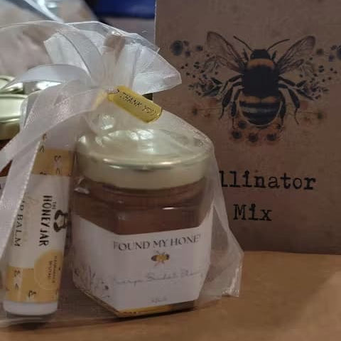 Jar of honey and balm with 'Found My Honey' wording, placed in front of a wooden box with a bee design.