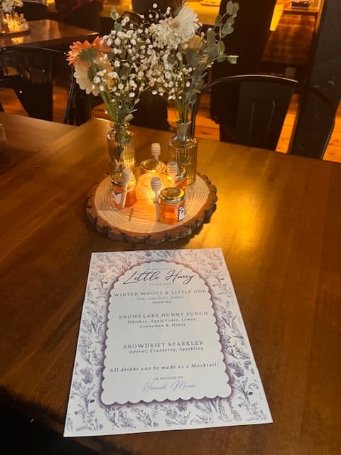 Table setting with a floral arrangement and a menu on a wooden table.