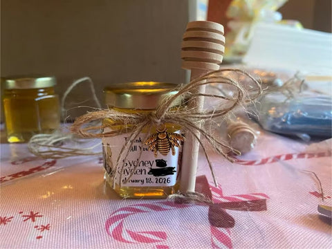 Small jar of honey with a honey dipper on a tablecloth