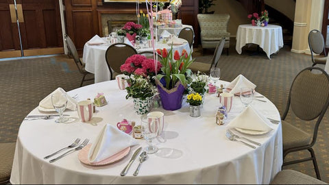 Decorated banquet hall with tables set for a meal, balloons, and flowers.
