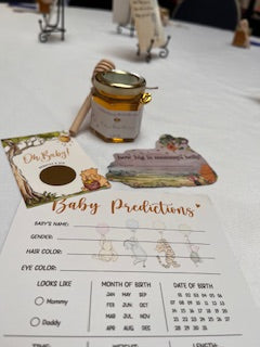 Baby shower game cards with a jar of honey on a white tablecloth