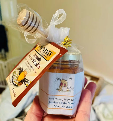 Bottle of honey with a label and decorative elements held by a hand.