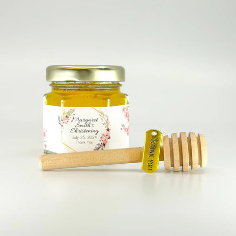 2 oz hexagon jar filled with honey, gold lid, 3" wooden honey dipper, gold Thank You charm, and personalized pink and gold frame design on label with title Thank You.