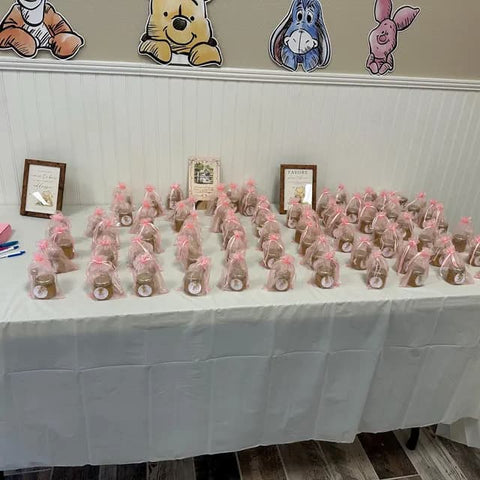 Table with small wrapped gifts on a white tablecloth, Winnie the Pooh decorations on the wall.