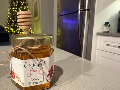 Jar of honey with a decorative label on a kitchen counter, Christmas lights in the background