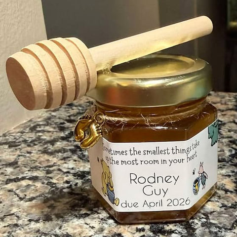 Jar of honey with a wooden dipper on a countertop, featuring a personalized label.