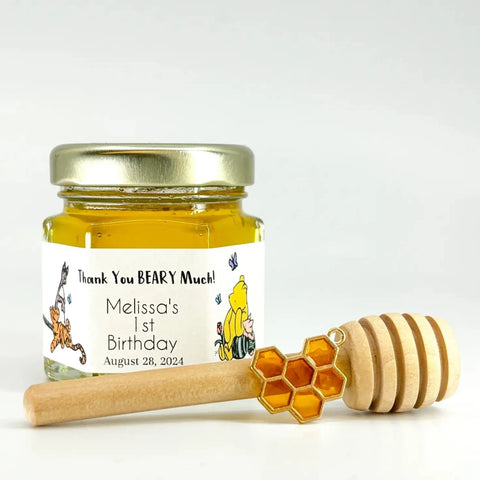 2 oz honey baby shower favor with gold lid, 3" wooden honey dipper, enamel honeycomb charm, and personalized label with Winnie the Pooh, Piglet, Tigger, and Kanga. Label title is Thank You BEARY Much.