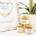 Wildflower theme baby shower favors with personalized Baby to Bee label and gold lid. Free printable sign is in the background with title Baby to Bee.