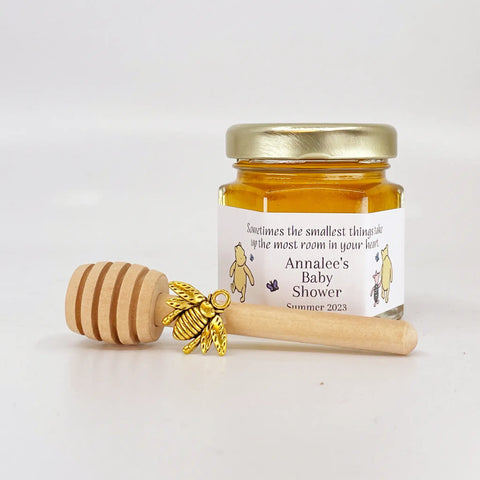 2 oz hexagon jar filled with honey, gold lid, gold bee charm, 3" wooden honey dipper and personalized Winnie the Pooh design on label with butterflies and title that says Sometimes the smallest things take up the most room in your heart.