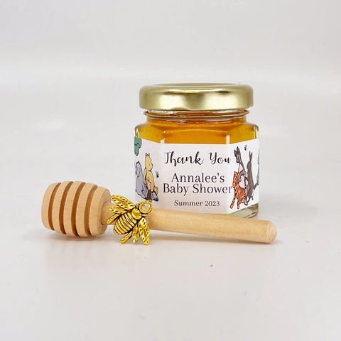 2 oz hexagon jar filled with honey, gold lid, gold bee charm, 3" wooden honey dipper and personalized Winnie the Pooh design on label with Winnie the Pooh, Eeyore, Piglet, Tigger, Kanga, and Rabbit and title that says Thank You.