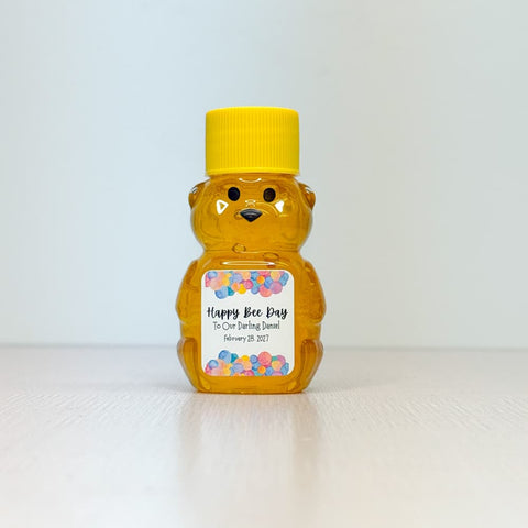 honey bear with yellow cap and personalized colorful label on neutral background