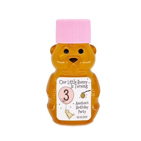 2 oz honey bear baby shower favor with pink cap and personalized label. Label shows classic Winnie the Pooh with a pink balloon with the title Our Little Hunny is Turning 3.