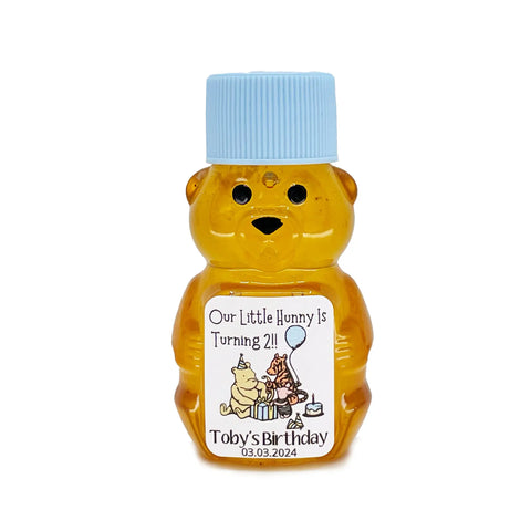 2 oz Winnie the Pooh honey bear baby shower favor with baby blue cap and personalized label. Label shows classic Winnie the Pooh, Piglet, and Tigger with blue party decorations with the title Our Little Hunny is Turning 2.