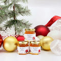 2 oz honey holiday Christmas party favor gift jars shown with gold lid and personalized Christmas ornament labels. Labels feature Bee-lieve title. Christmas ornaments and tree in background.