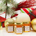 Close up of 2 oz honey holiday Christmas party favor gift jars with gold lid and personalized labels. Labels feature holiday lights and Bee Happy title. Christmas decorations in background.