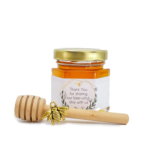 2 oz hexagon jar filled with honey, gold lid, 3" wooden honey dipper, gold bee charm, and geometric frame design on label with title that says Thank You for sharing our bee-utiful day with us.