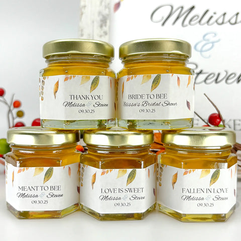 Close up for 2 oz hexagon honey wedding favors with gold lids and autumn leaves labels. Label titles include Thank You, Bride to Bee, Meant to Bee, Love is Sweet, and Fallen in Love.