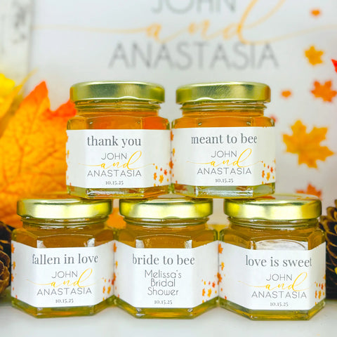 Group of 2 oz honey wedding favors with gold lids and fall trees labels. Label titles include Thank You, Meant to Bee, Fallen in Love, Bride to Bee, and Love is Sweet.