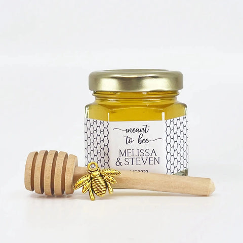 set options shown include honey, 2 oz hexagon jar, gold lid, 3" wooden honey dipper, gold bee charm, and personalized label with honeycomb theme. Title on label is Meant to Bee.