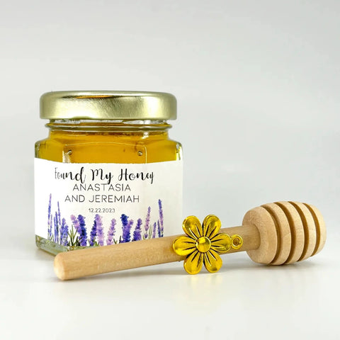 Full honey favor set shown with 2 oz hexagon jar filled with honey and topped with gold lid. Accessories include Lavender field label with Found My Honey title, 3" wodden honey dipper, and gold flower charm.