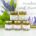 2 oz honey wedding favors in 2 hexagon jars with gold lids and personalized lavender themed labels. There are two label designs: lavender field and lavender bunch. Titles shown include Bride to Bee, Thank You, Meant to Bee, Found My Honey, and Welcome.