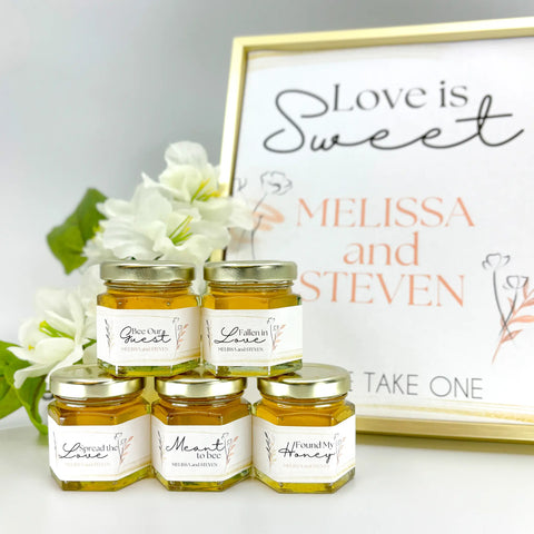 Honey wedding favors with free printable sign. Titles include Bee Our Guest, Fallen in Love, Love is Sweet, Spread the Love, Meant to Bee, , Found My Honey, and more. Contents include honey, 2 oz jar, personalized label, and gold lid.